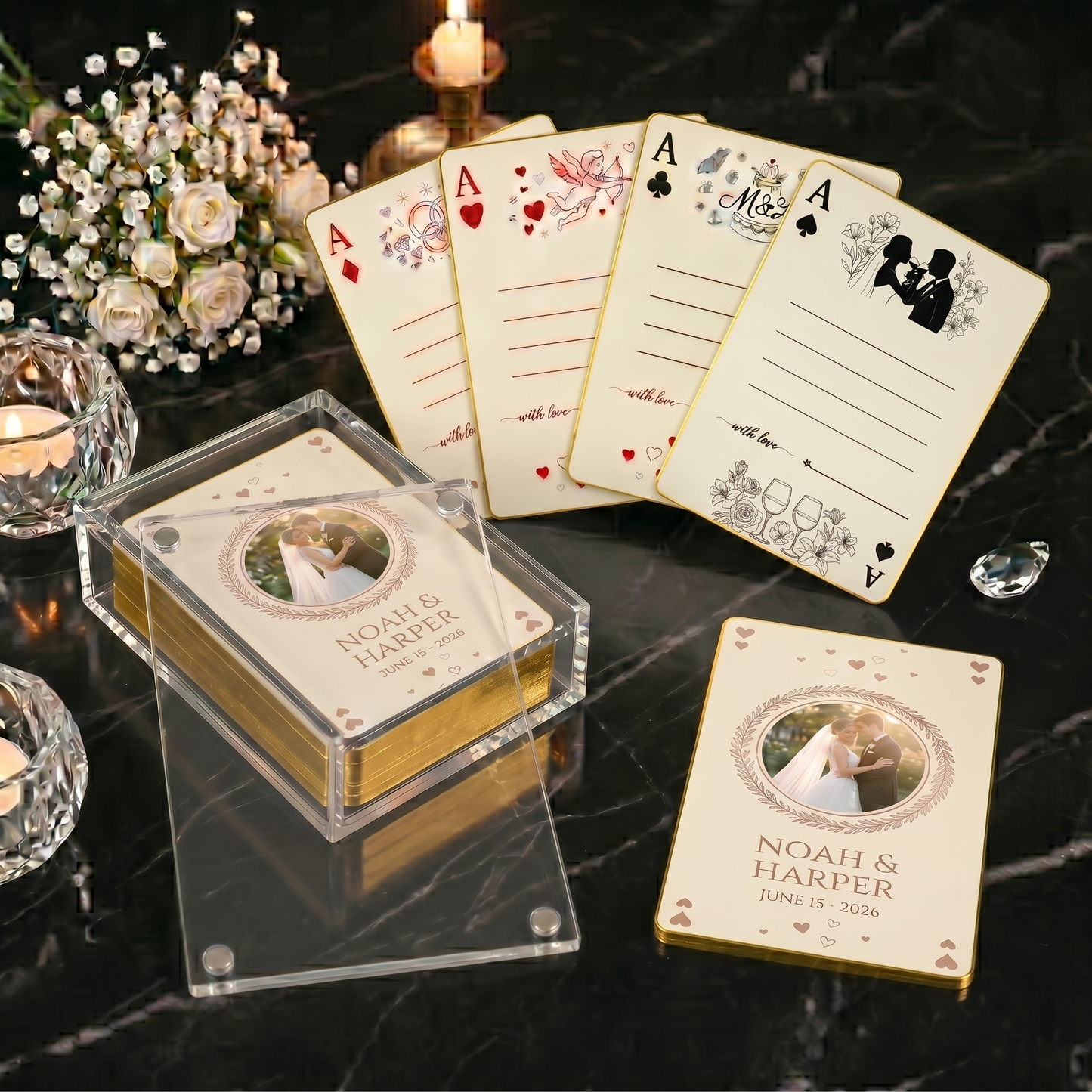 Custom wedding playing cards in a clear acrylic display box with gold-edged cards and four signature card designs on black marble with white roses